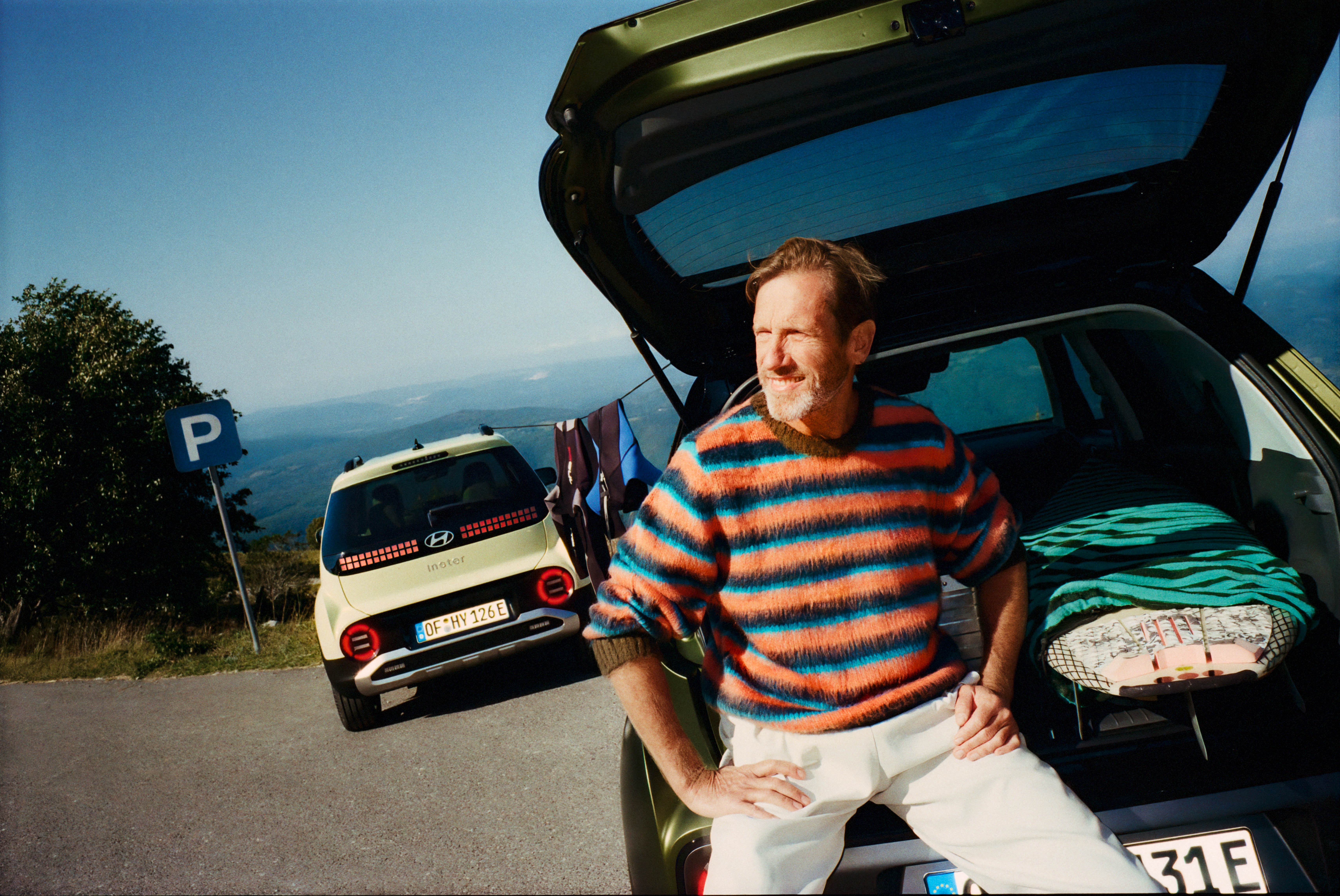 A man sitting in the opnend trunk of the new Hyundai INSTER small electric car. 